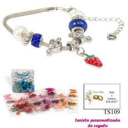 Pulsera con piedras blancas y azul electrico y un colgante de fresa